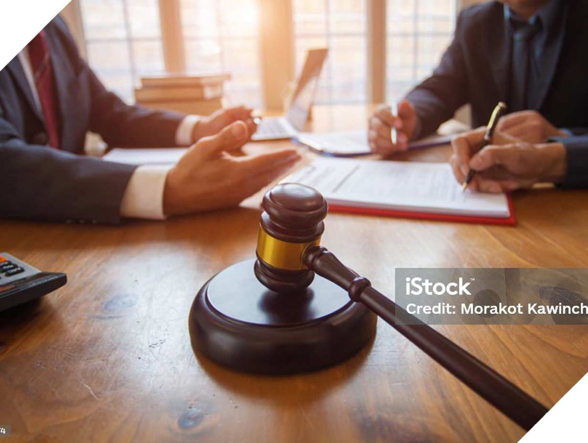 Two men sitting at table with gavel in middle of table