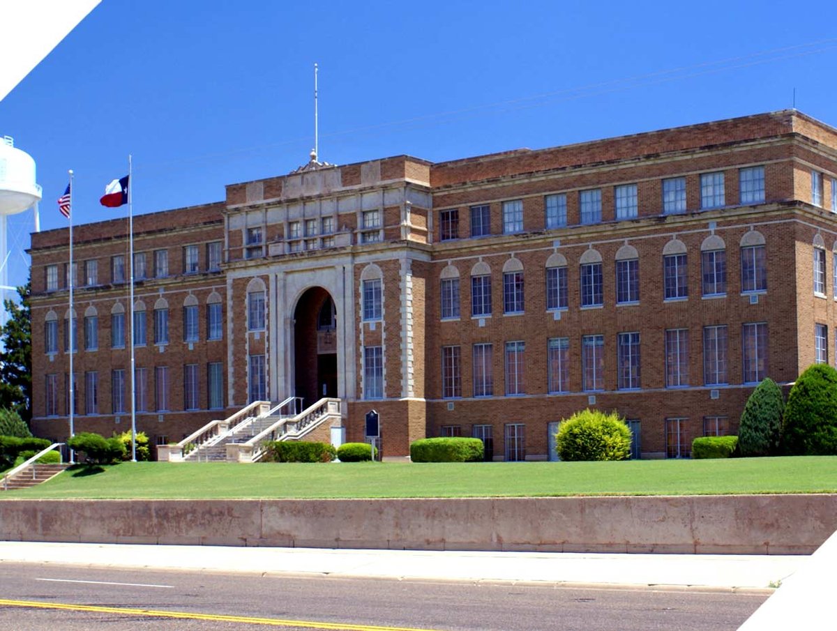 Outside of large 3 story school building on a sunny day